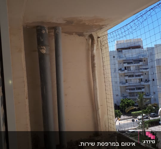 קיר עם צינורות מתכת וכתמי צבע מתקלפים